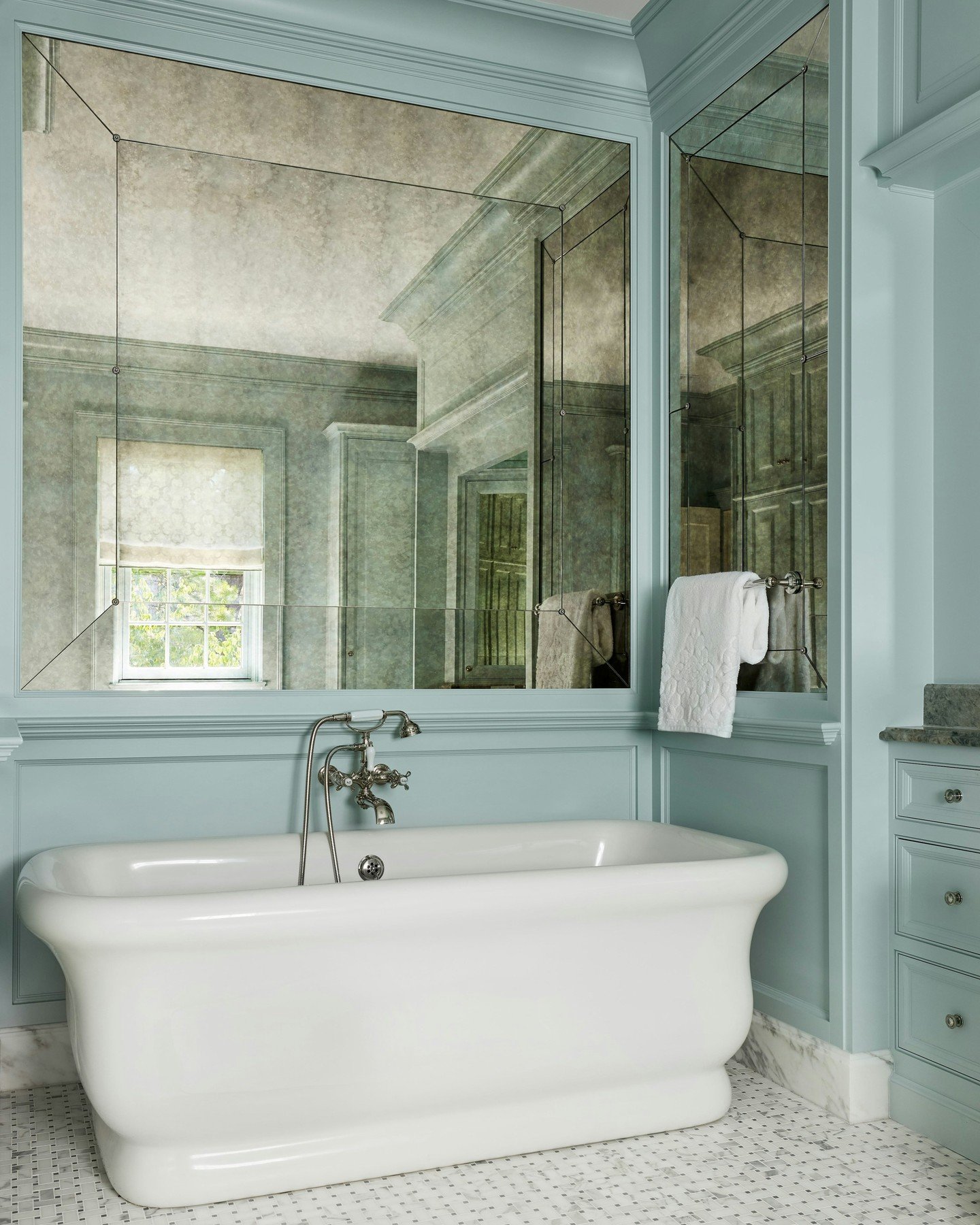 This primary bathroom is clad in antiqued mirror, its selection chosen to soften the light.